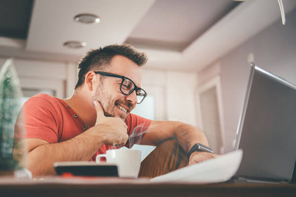 A man smiles at this computer. IdentityIQ offers identity restoration so that when you notice signs of identity theft you are protected.